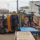 Truk muatan penuh sampah terbalik patah AS roda belakang kiri membuat jalan macet.