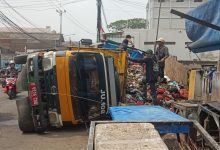 Truk muatan penuh sampah terbalik patah AS roda belakang kiri membuat jalan macet.